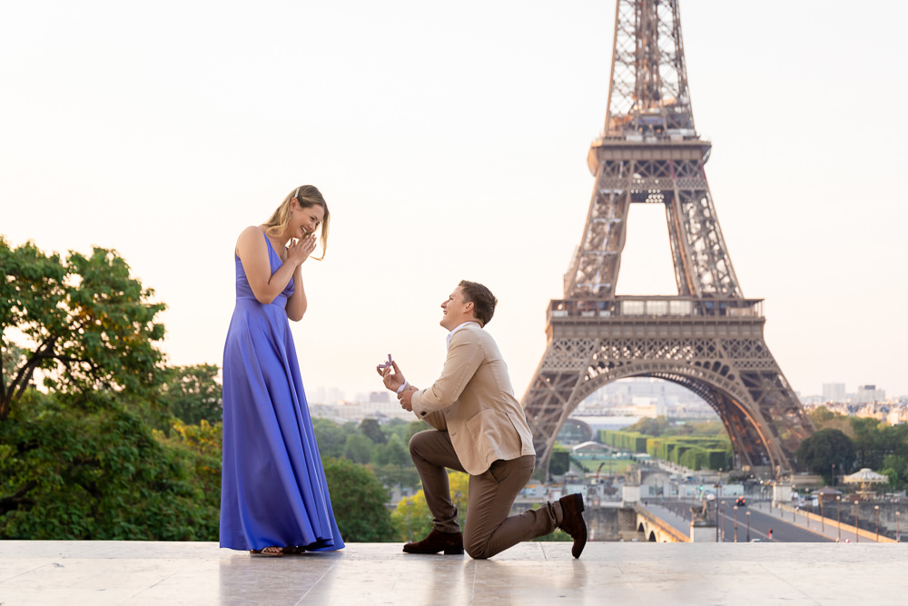 Man on his knee proposing in front of the Eiffel Tower at sunrise