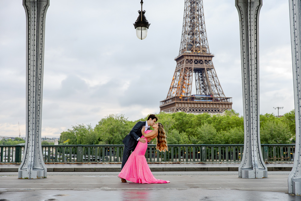 Couple in a dip kiss under the arches of Bir-Hakeim bridge, with the Eiffel Tower behind them, photographed by Lena, Paris couples photographer